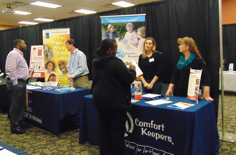 students speaking with company representatives at a career fair