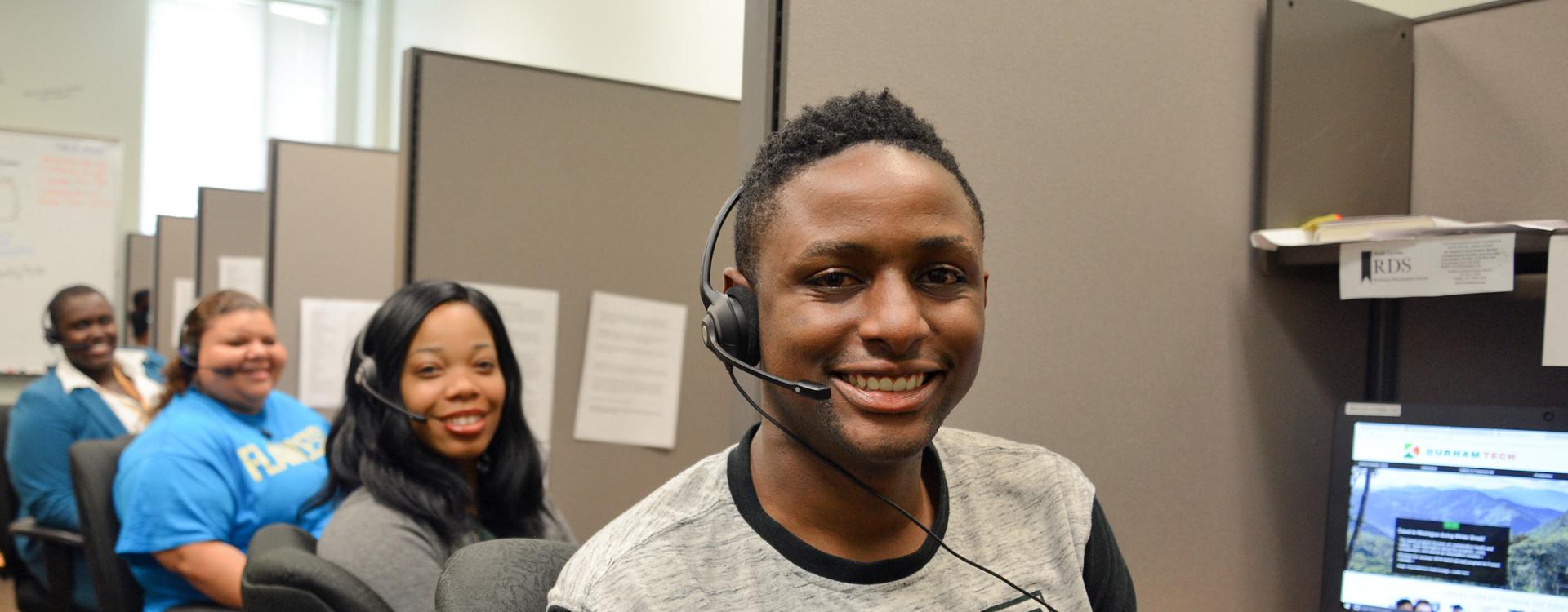 Student Communication Assistants facing camera wearing headphones to answer calls