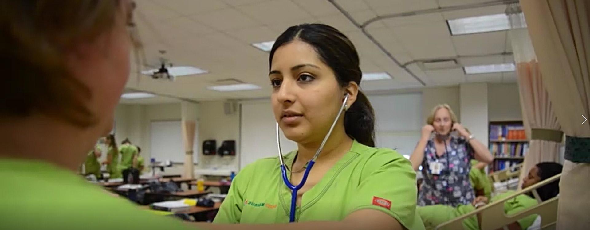 nursing student practices using stethescope in nursing lab